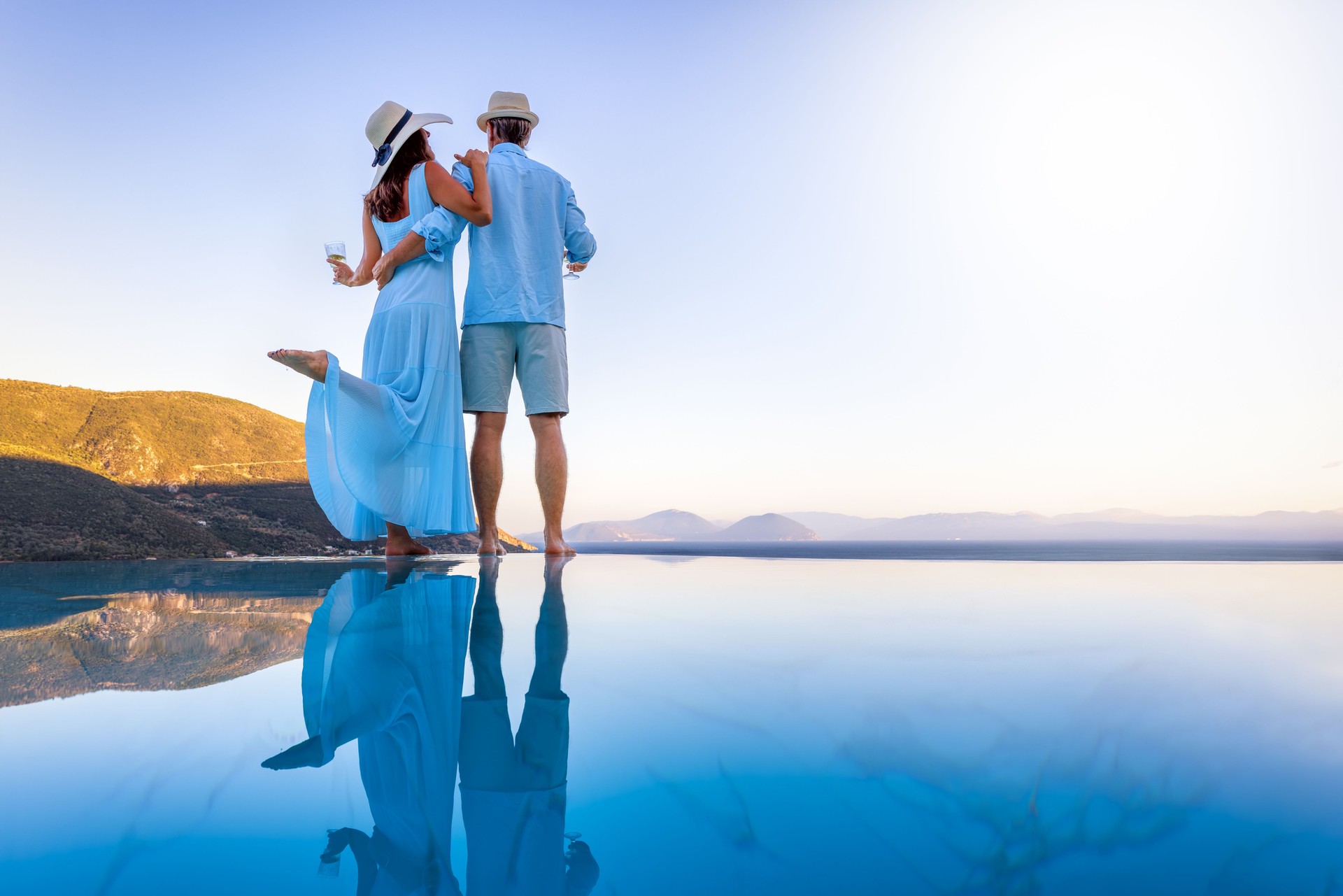 A elegant vacation or honeymoon couple enjoys the mediterranean sunset by the pool A elegant vacation or honeymoon couple enjoys the mediterranean sunset by the pool