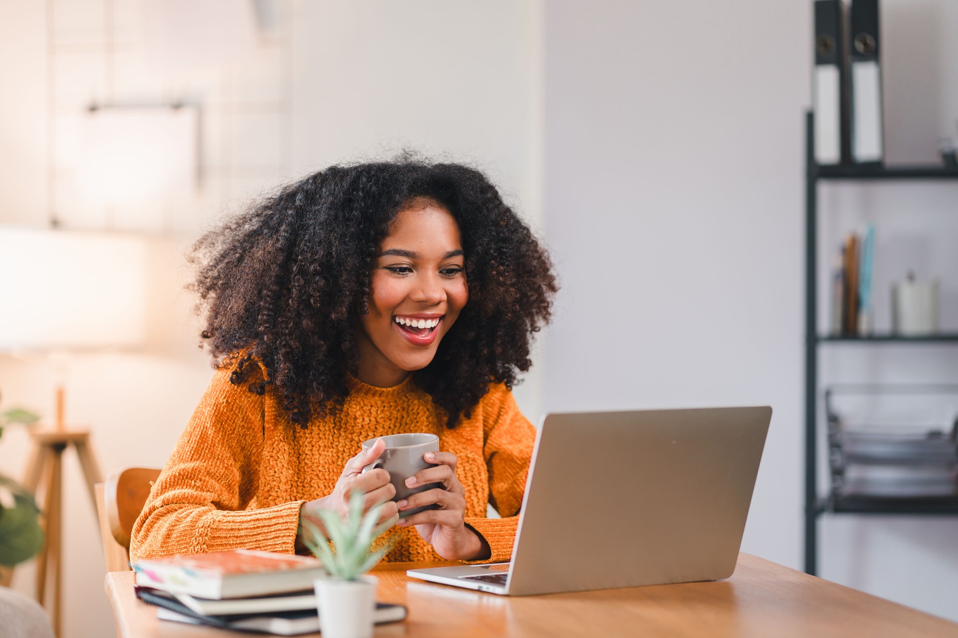 Smiling African American woman using a laptop while working from home. Smiling African American woman using a laptop while working from home.